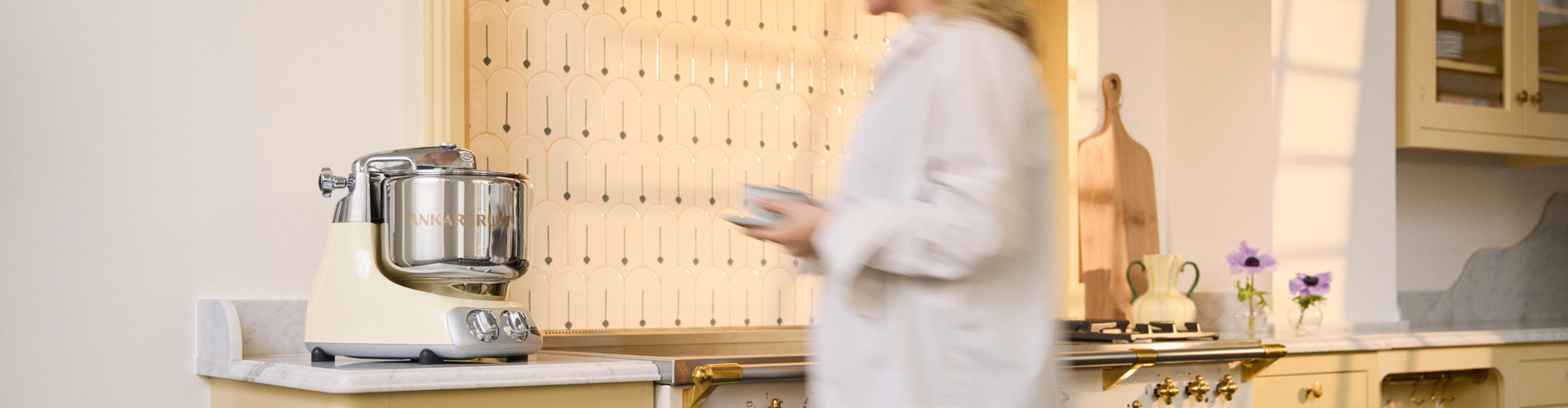 A woman standing in a kitchen next to a counter with a crema light stand mixer on it.