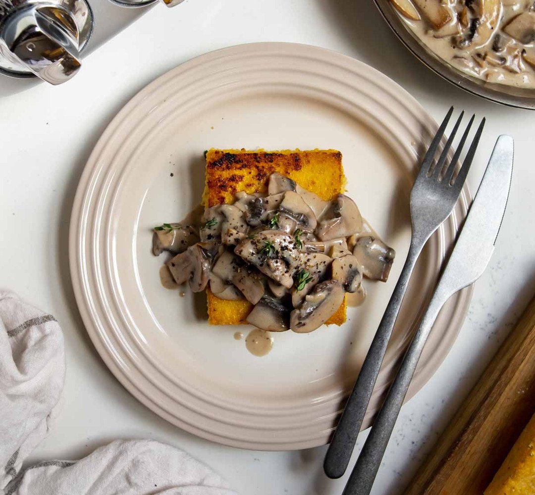 A plate with pan-fried polenta with mushroom sauce. 
