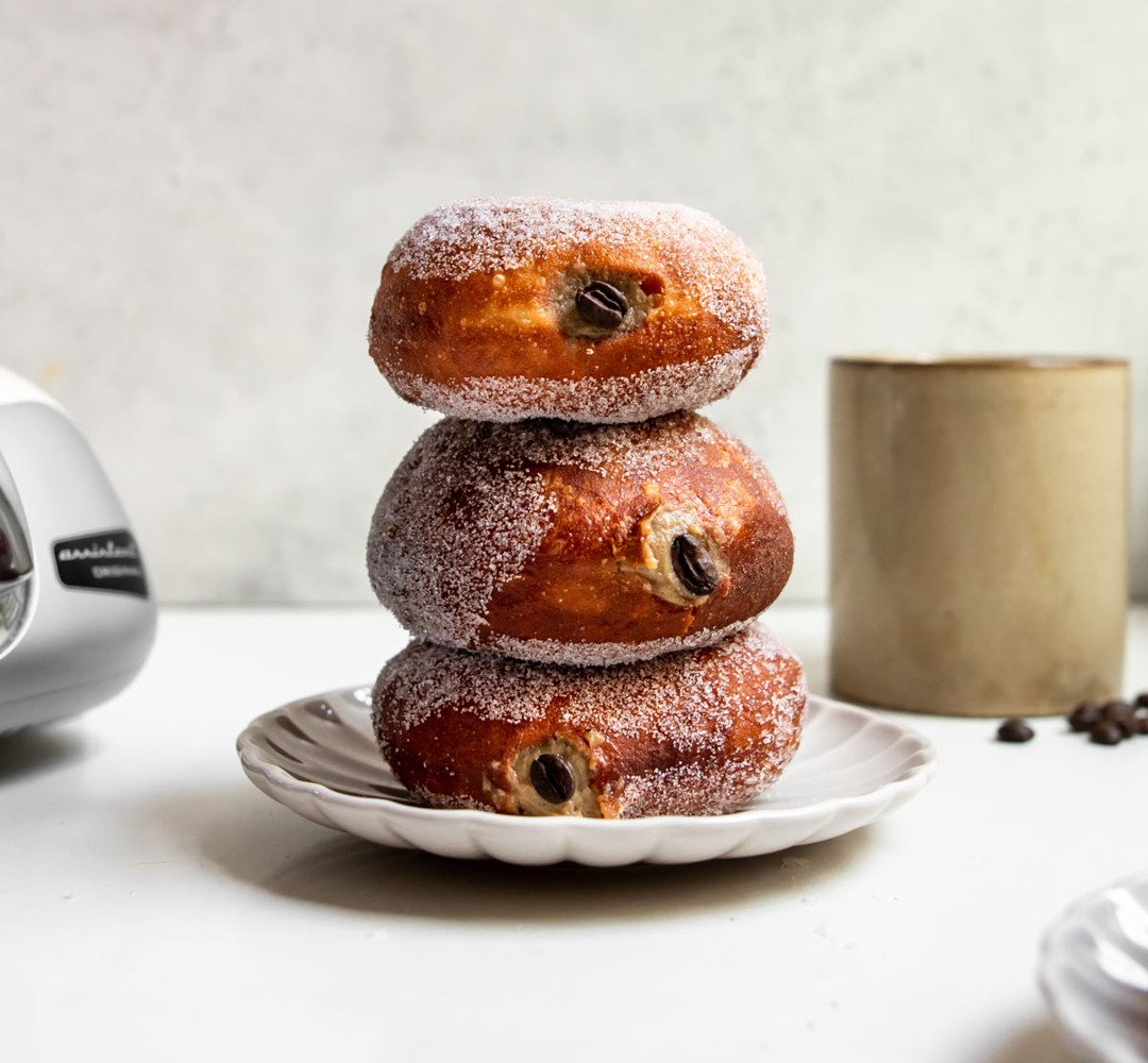 A stack of donuts filled with coffee cream sitting on top of a white plate.