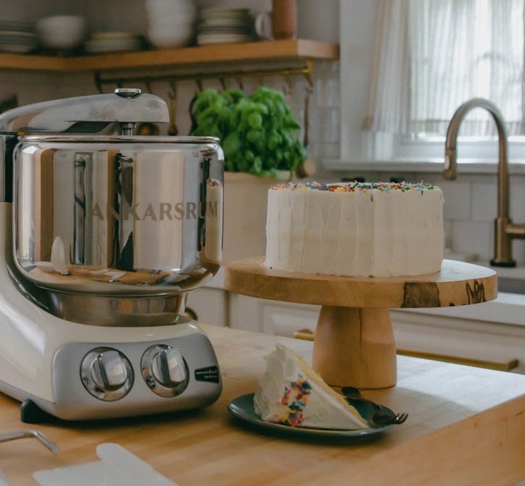Ankarsrum Assistent Original stand mixer on countertop with a vanilla birthday cake