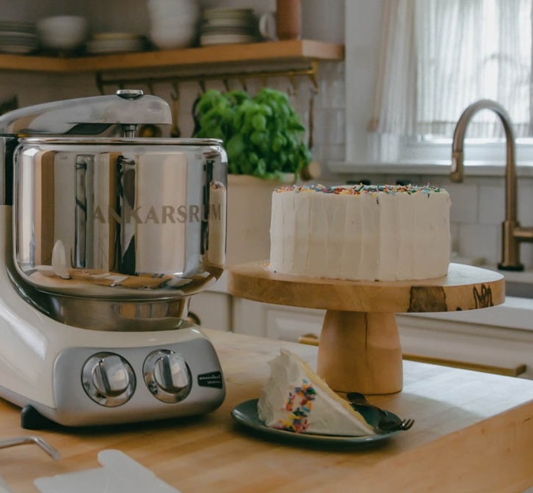 Ankarsrum Assistent Original stand mixer on countertop with a vanilla birthday cake