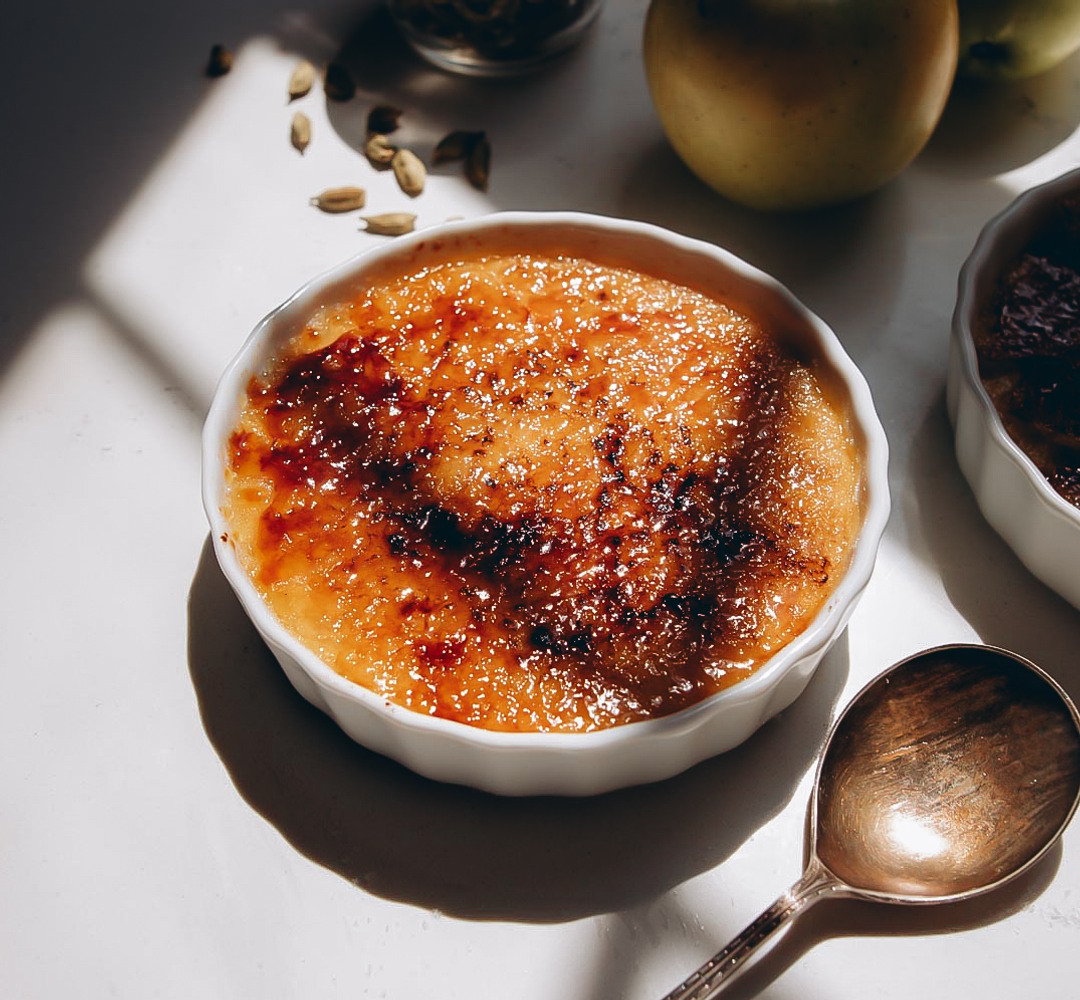 Crème brûlée i en portionsform, med en sked placerad bredvid.