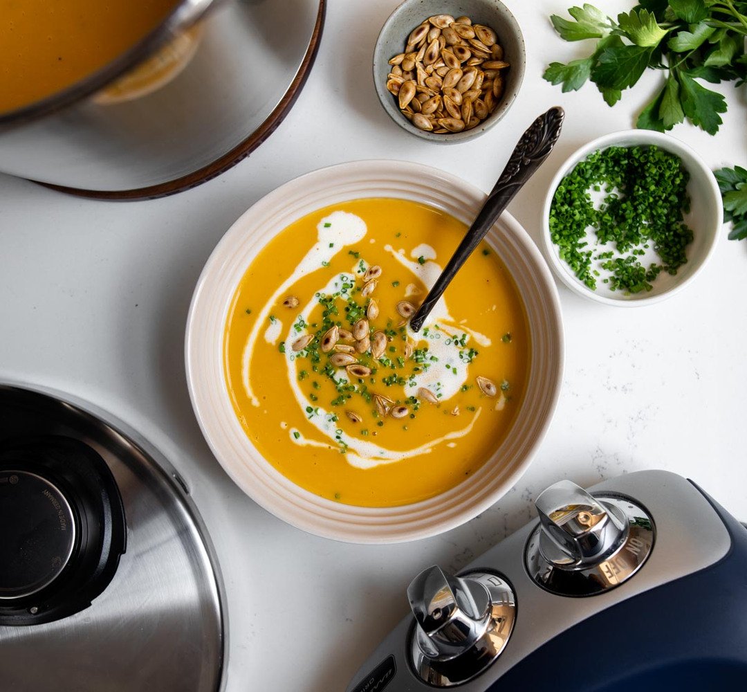 A bowl of squash soup with a spoon in it.