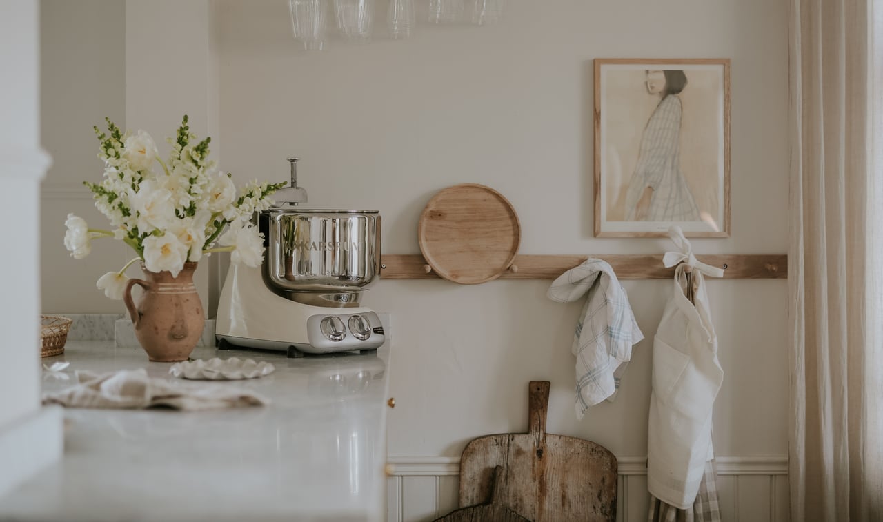 Ljus köksbänk i färgen Ankarsrum Assistent Creme Light med en vas med blommor.