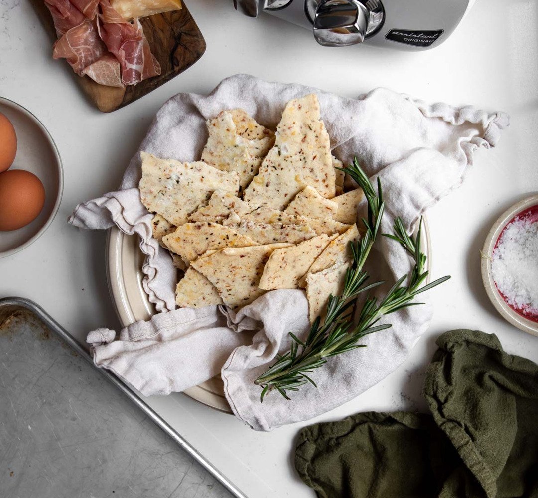 Prosciutto Parm Meringue Crisps in a bowl with a cloth on a white table.