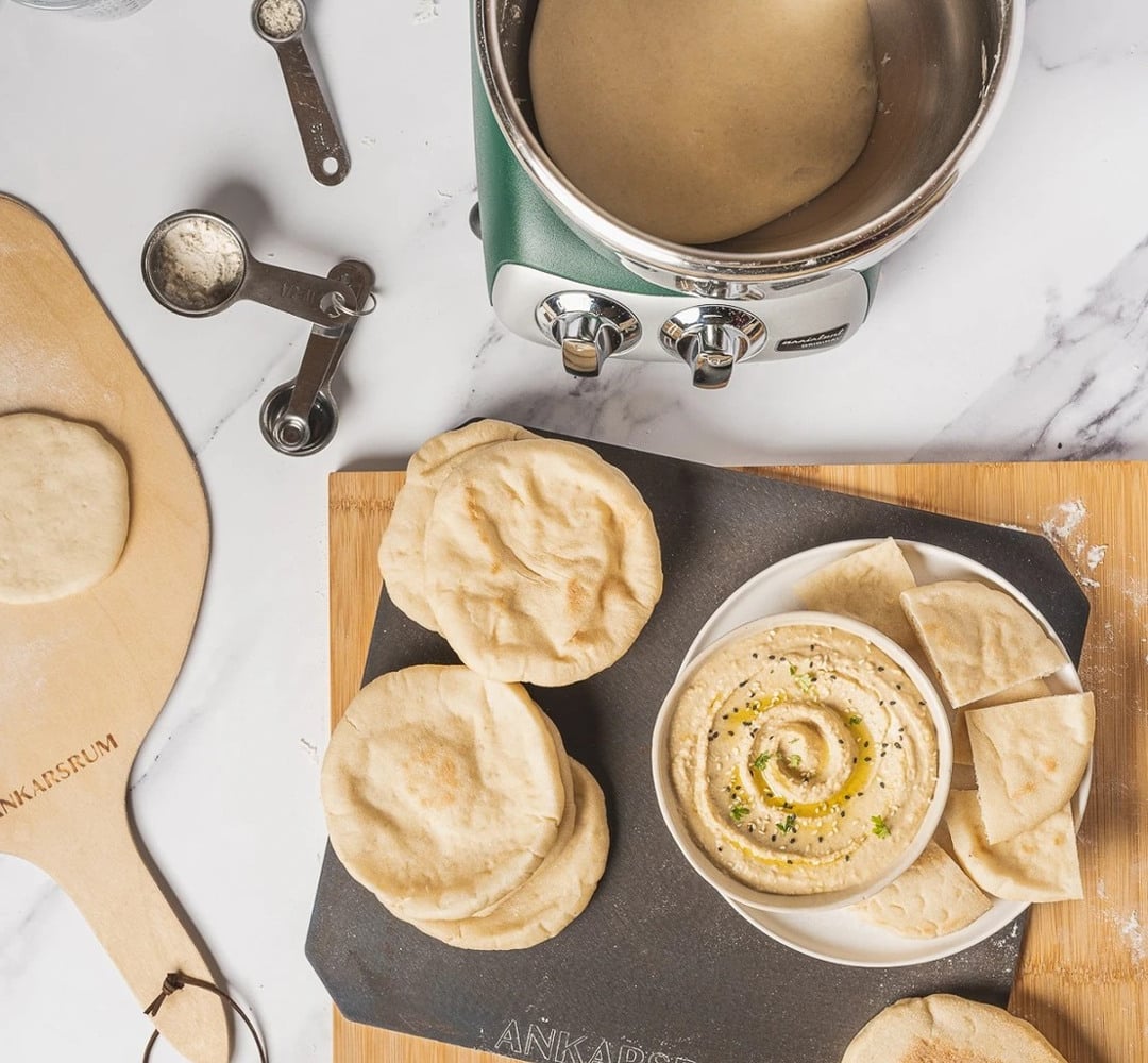 A plate of pita bread next to a pot of Hummus.
