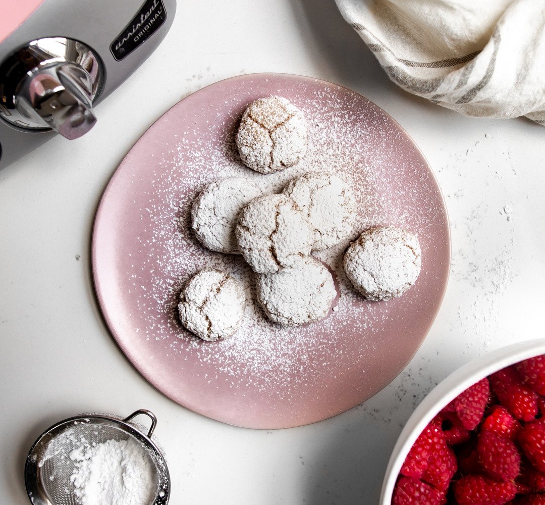 Raspberry Amaretti Cookies on a pink plate on a kitchen countertop.