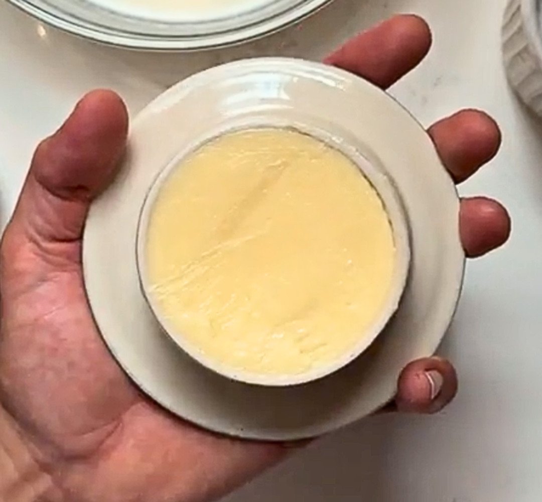 A person holding a white butter crock with butter inside.