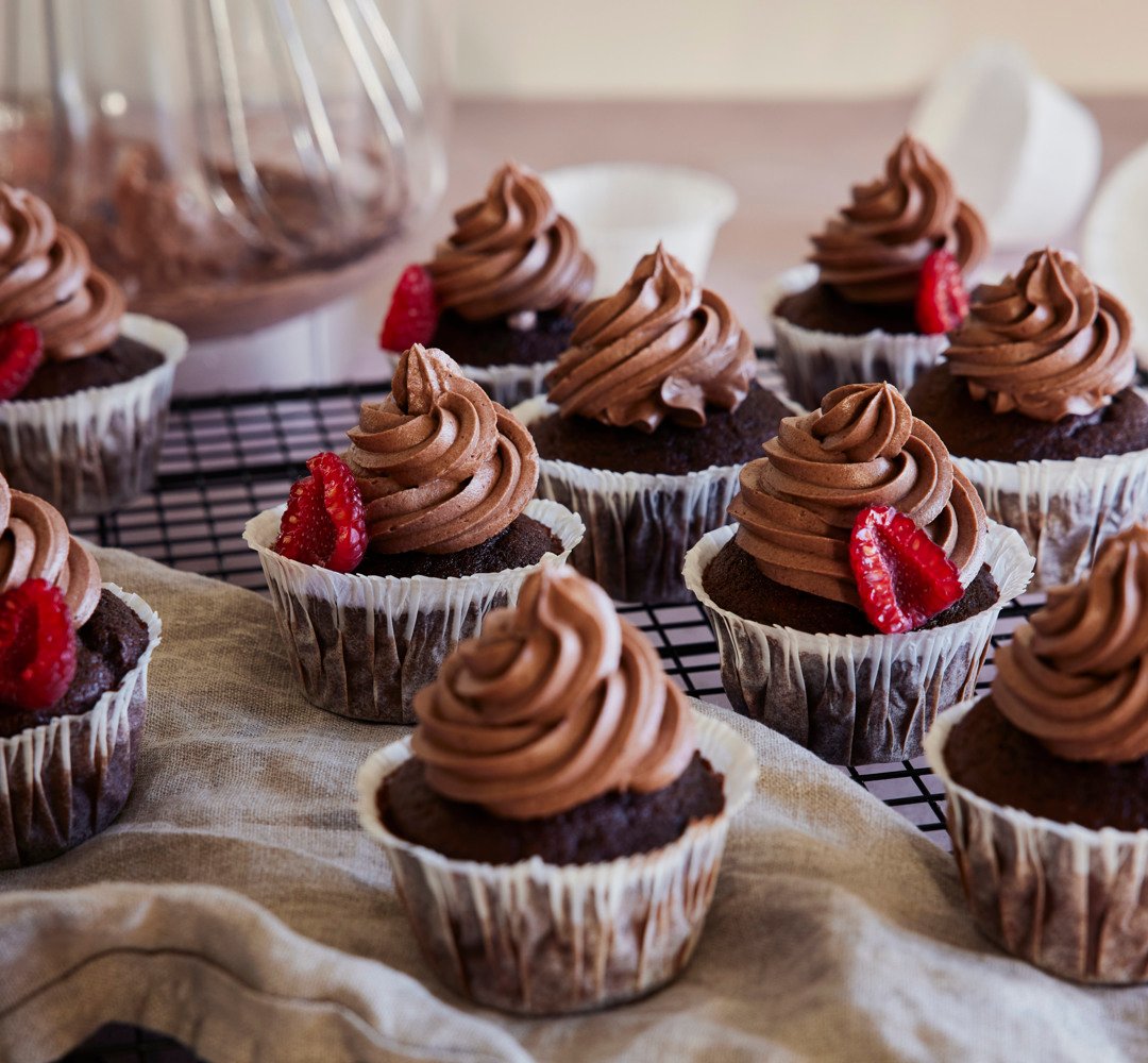 Chokladmuffins med chokladfrosting och jordgubbar på ett avkylningsgaller.