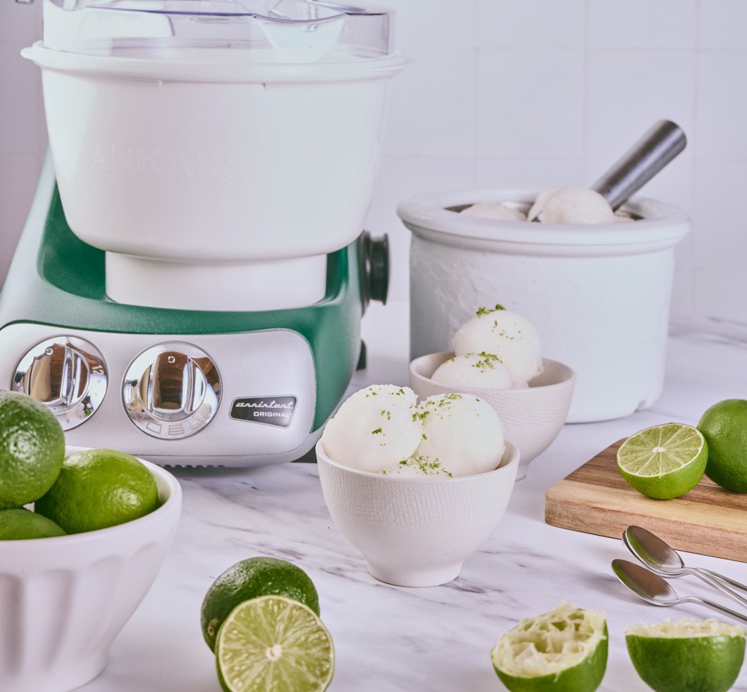 Skålar med lime-sorbet på ett bord, omgivna av färska limer. Ankarsrum glassmaskin i bakgrunden.