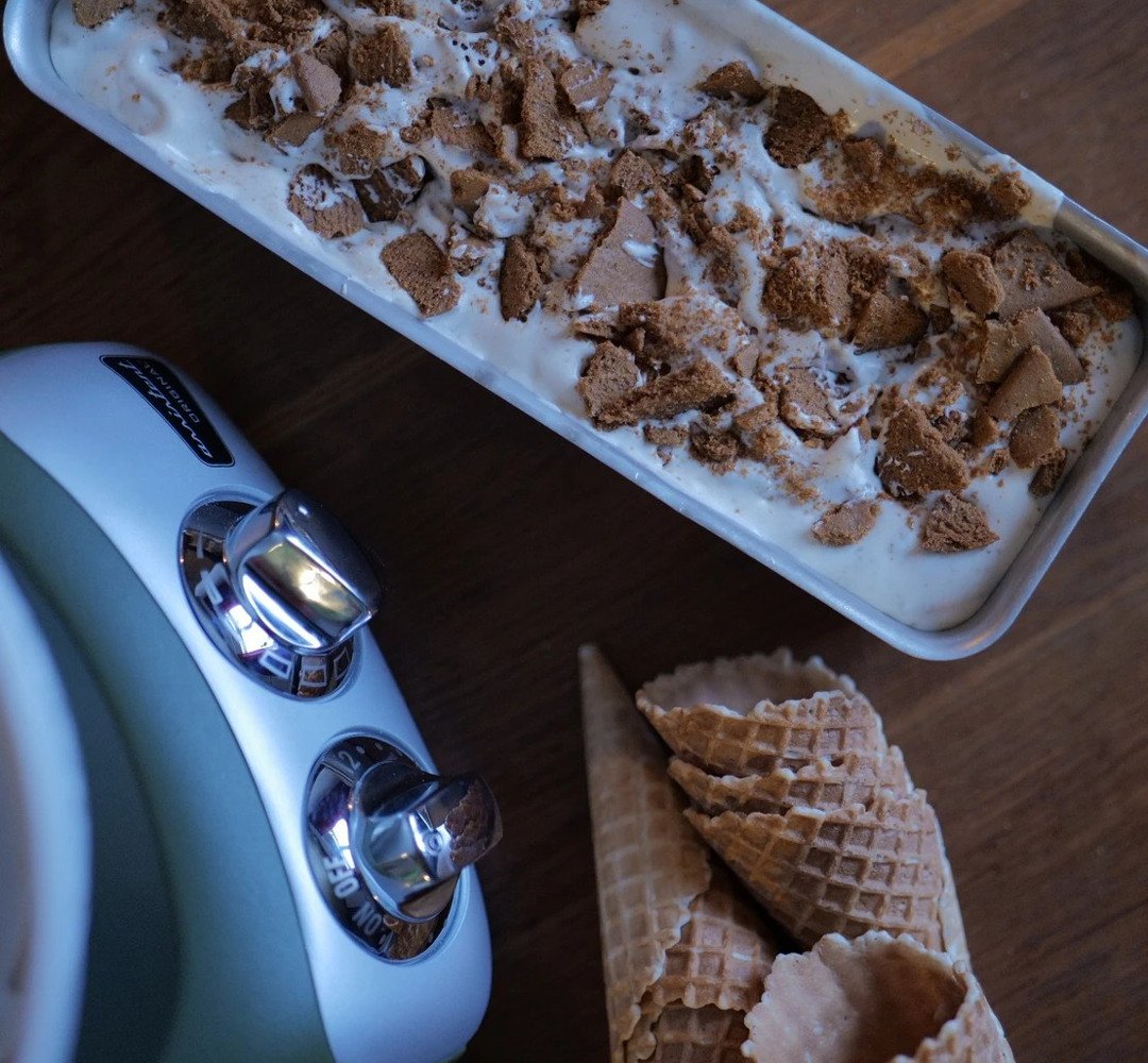 A pan of ice cream next to an ice cream maker.