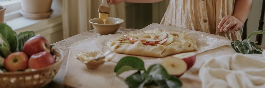 Ett bord fyllt med olika rätter: bröd, våfflor, bär och juice i en citruspress. En Ankarsrum Assistent i skogsgrön står också på bordet.