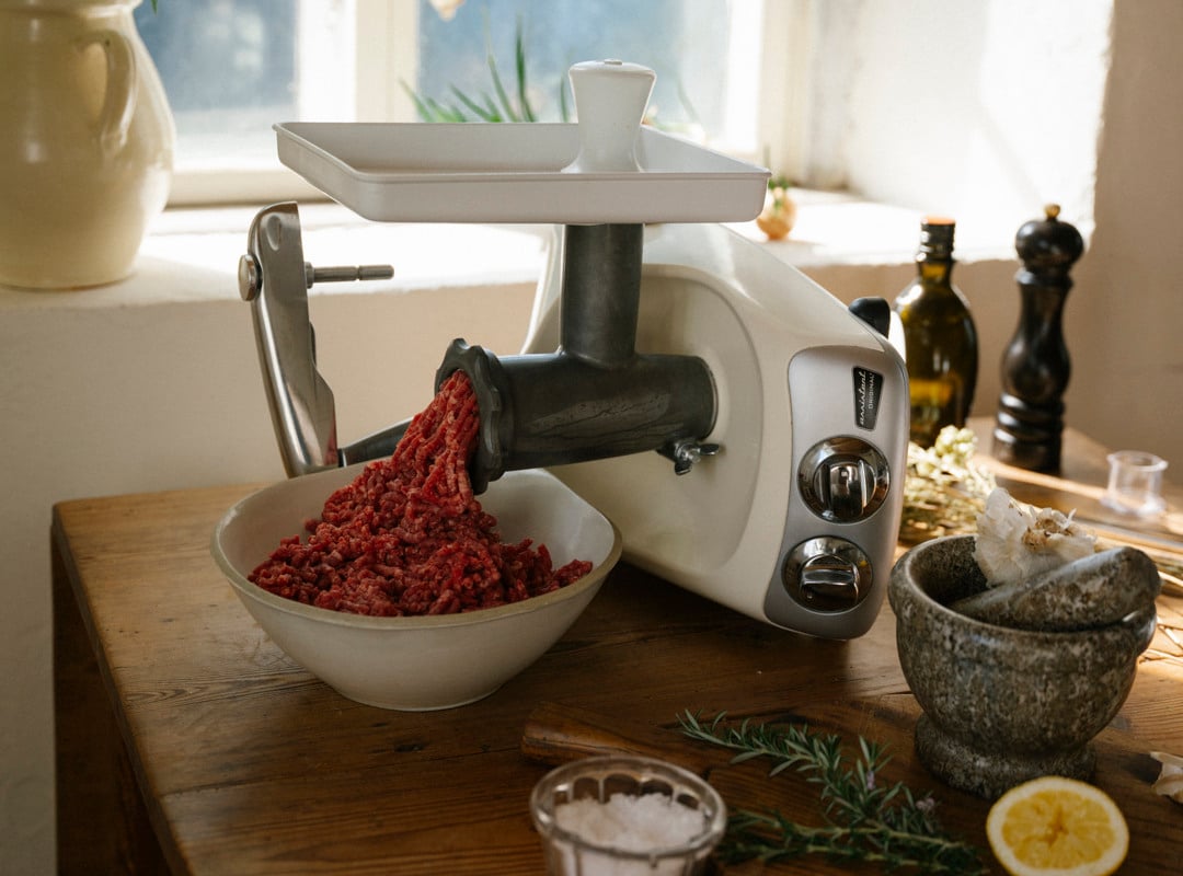 Meat is being grind in a mincer attached to Ankarsrum assistent original.