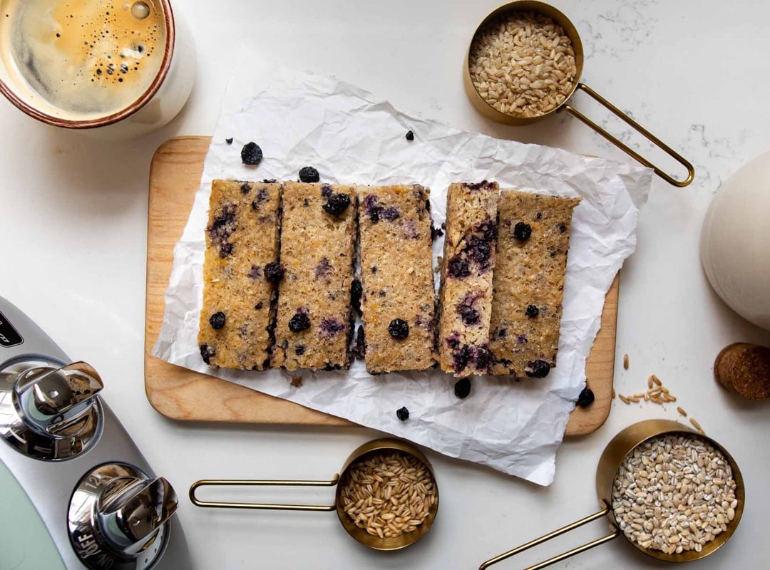 3-grain breakfast bars with blueberries on a wooden cutting board.