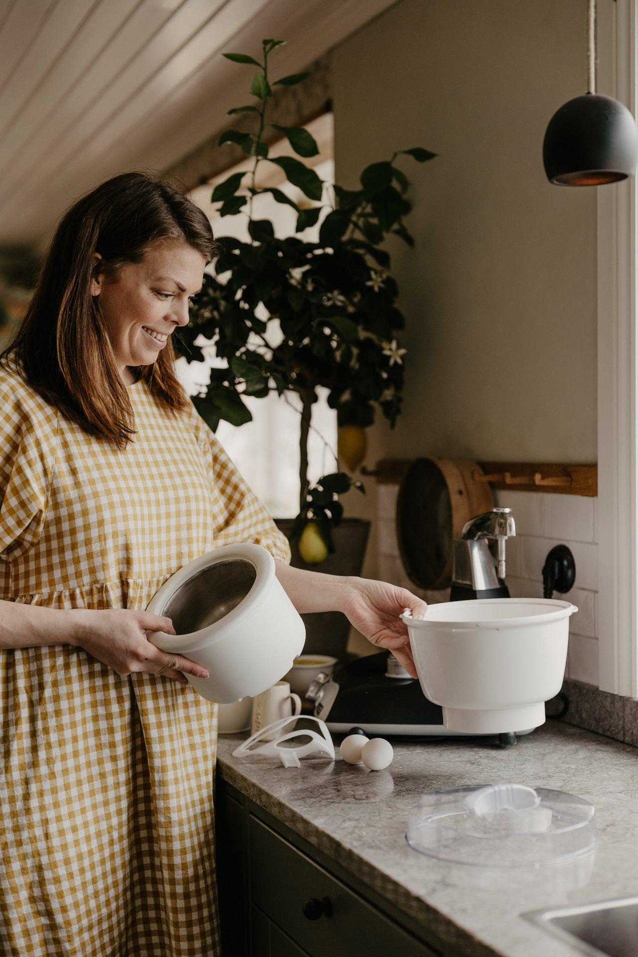 A woman holding a ice cream mixer bowl in the kitchen.