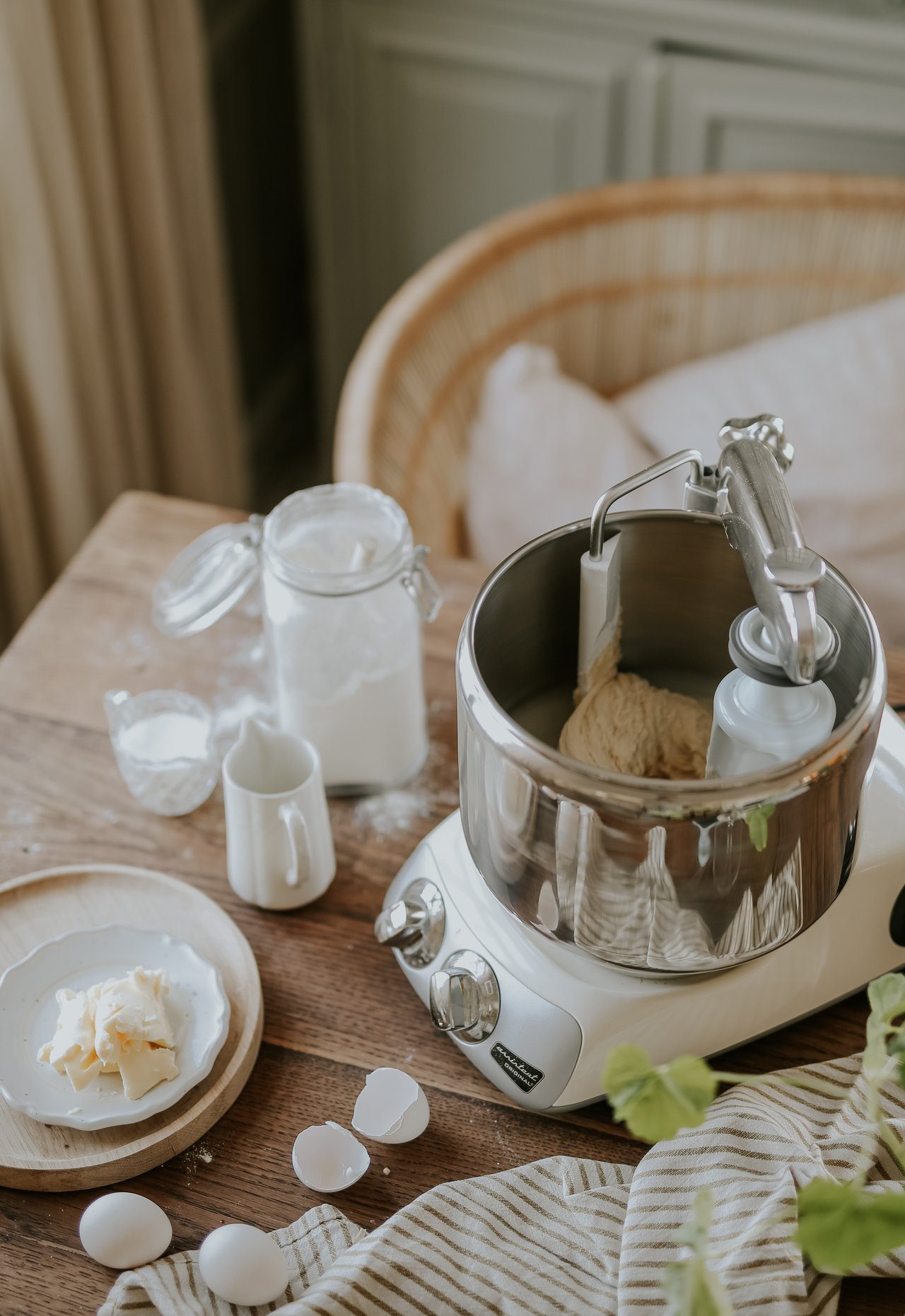 A stand mixer mixing dough sitting on top of a wooden table.