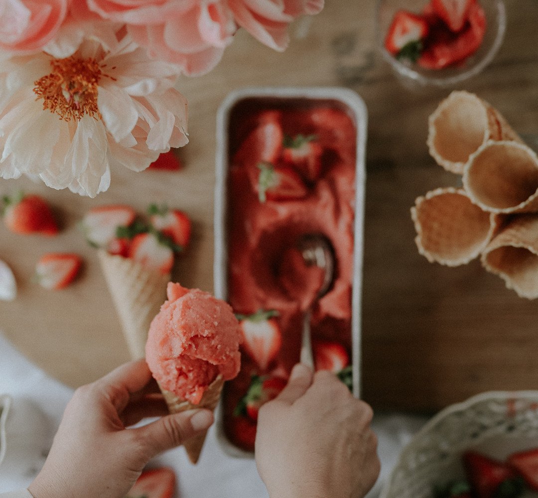 A person is eating a strawberry ice cream.