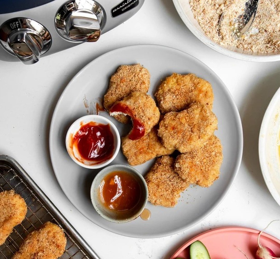 Kycklingnuggets på en tallrik med skålar med ketchup vid sidan om.