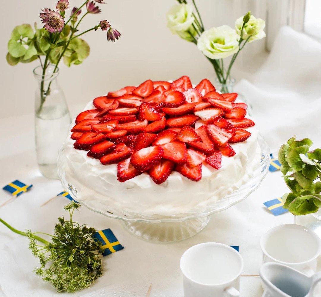 En tårta med jordgubbar på toppen som står på ett bord.