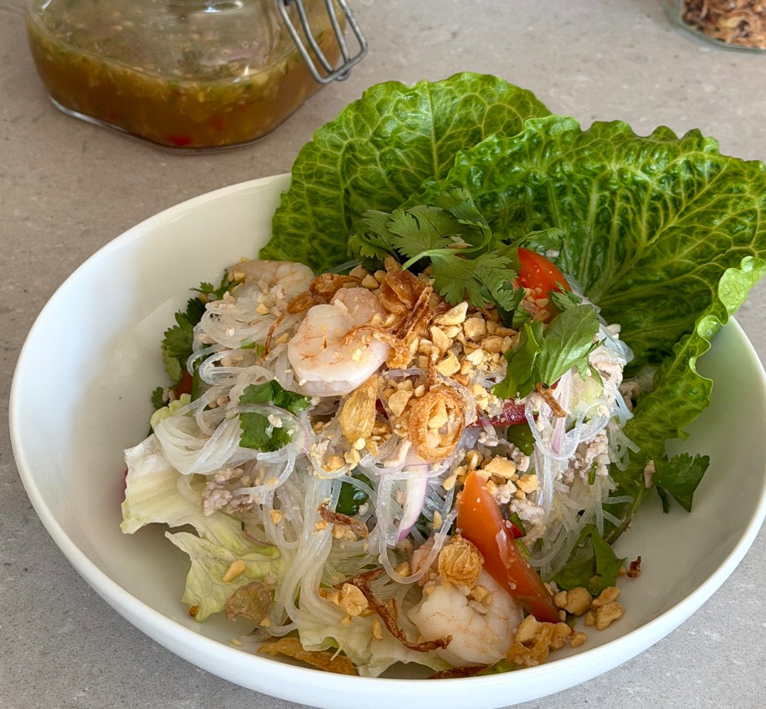 Den thailändska rätten Yam Woon Sen, serverad på en vit tallrik tillsammans med en syrlig dressing.