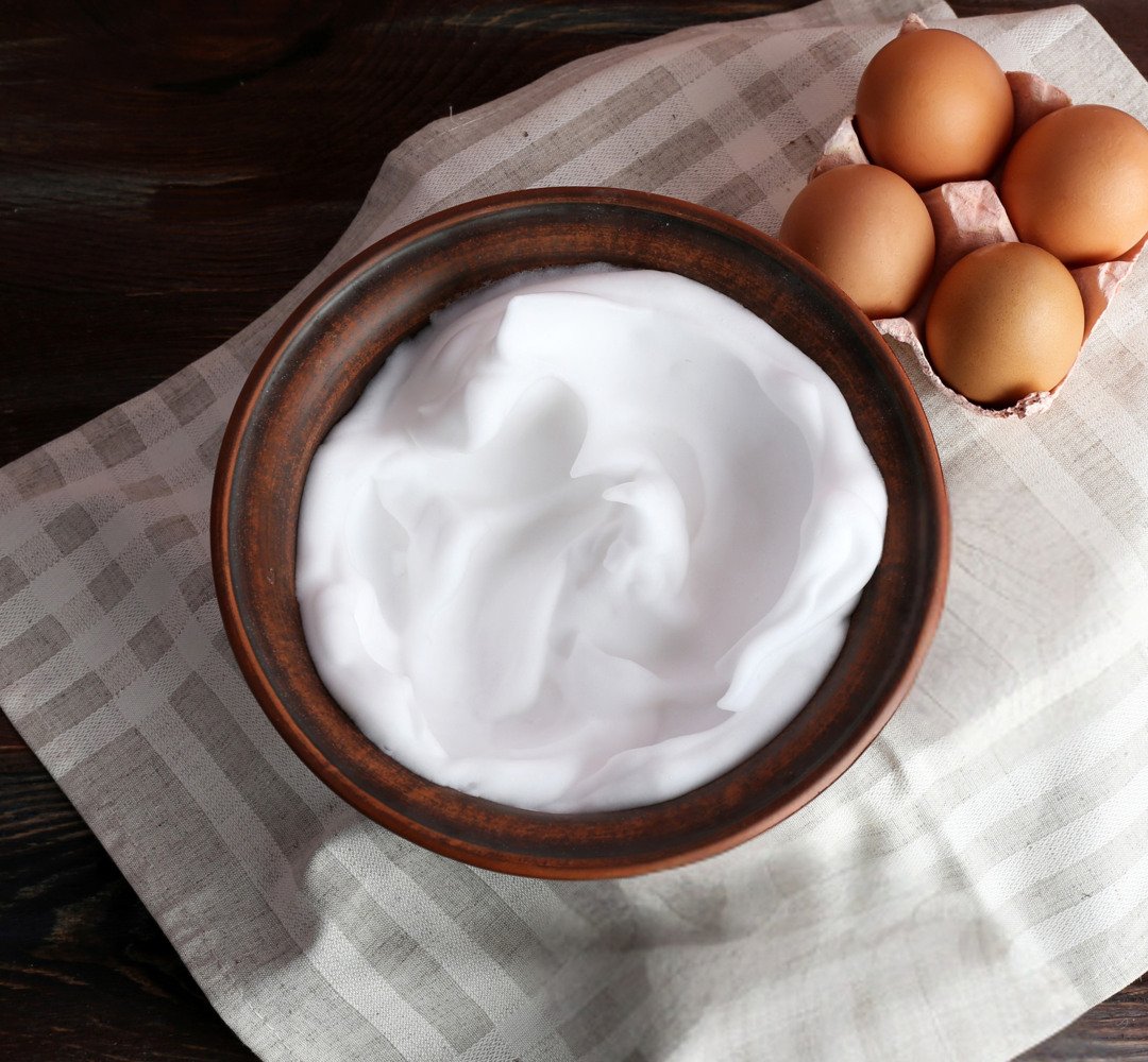 A bowl of whipped eggs next to eggs on a napkin.
