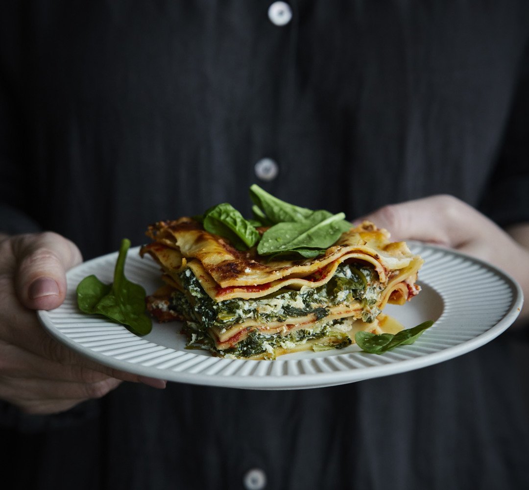En person som håller en tallrik med lasagne.