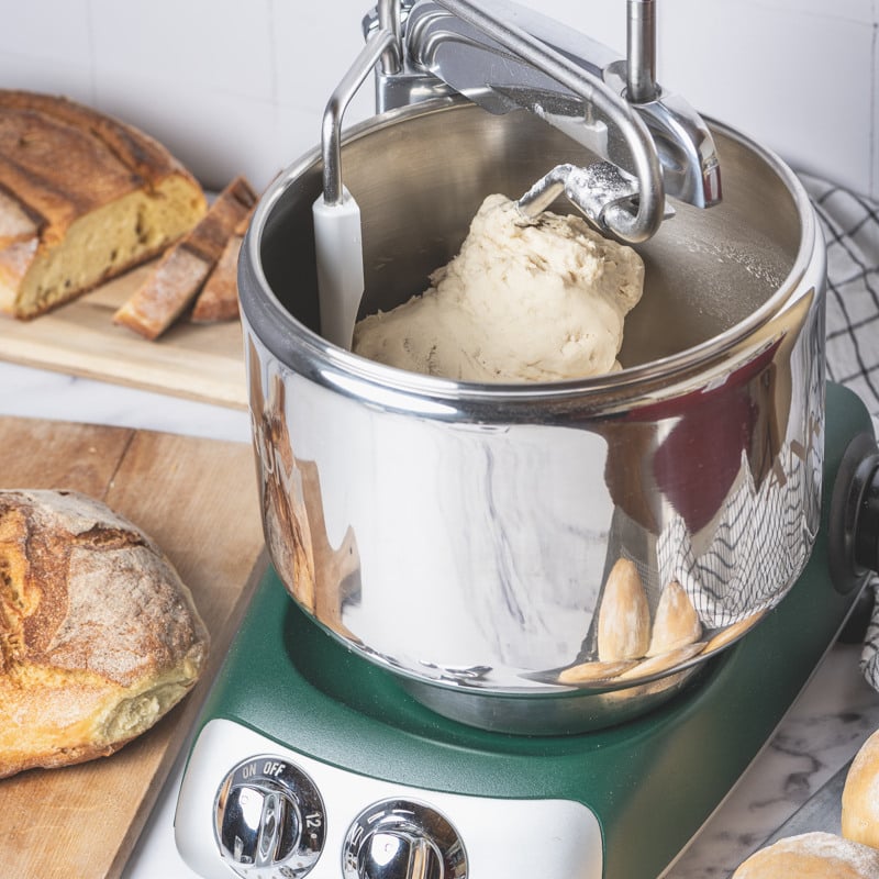 Ankarsrum assistent i skogsgrön, stående på en bänk. Bakning av bröd.