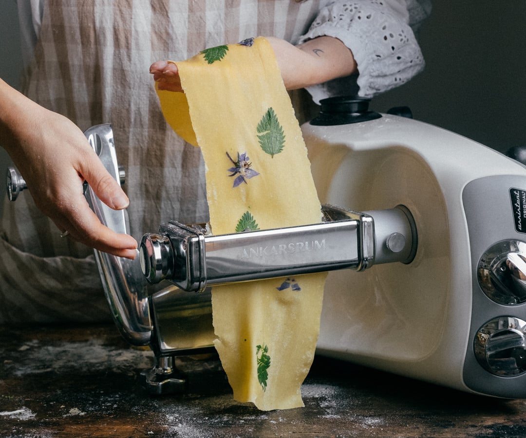 A woman using a pasta cutter to make pasta.