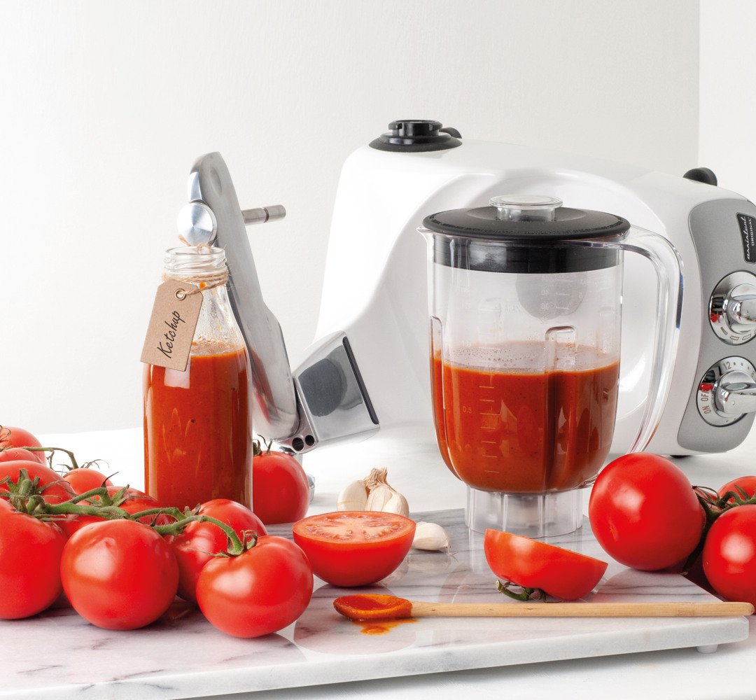 En mixer fylld med hemlagad ketchup, bredvid tomater.