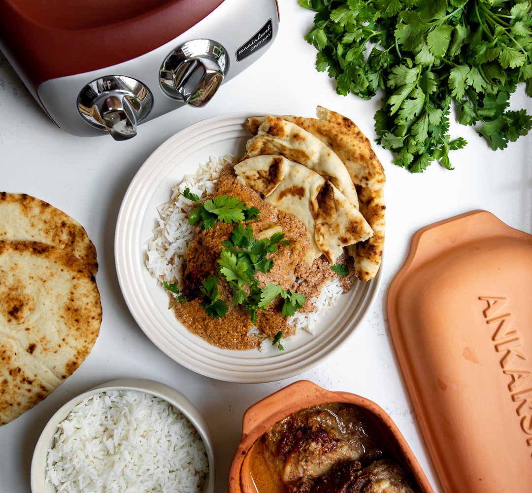 A table topped with plate of naan and chicken over rice.