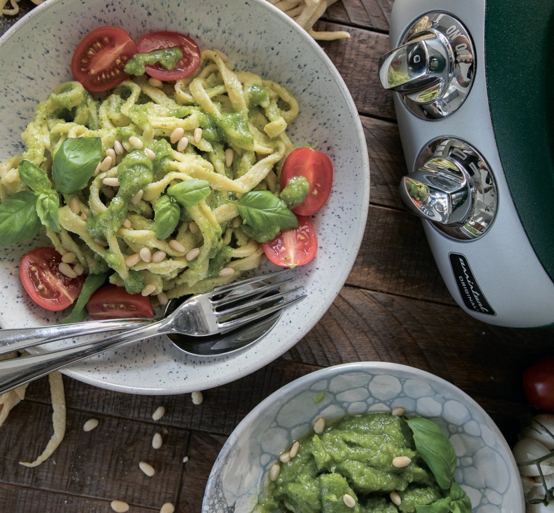 En skål med pasta med pesto och tomater.