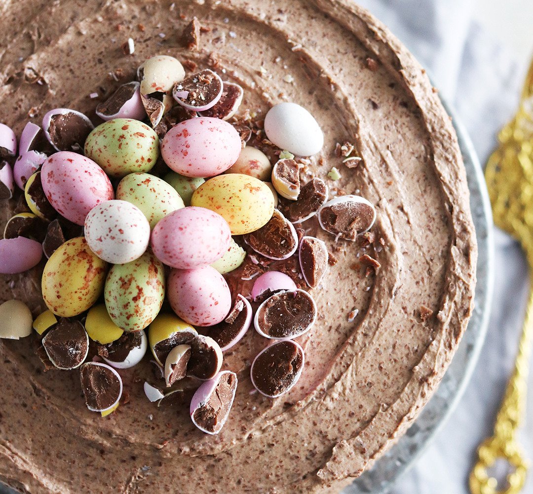 En tårta med chokladfrosting och chokladägg på toppen.