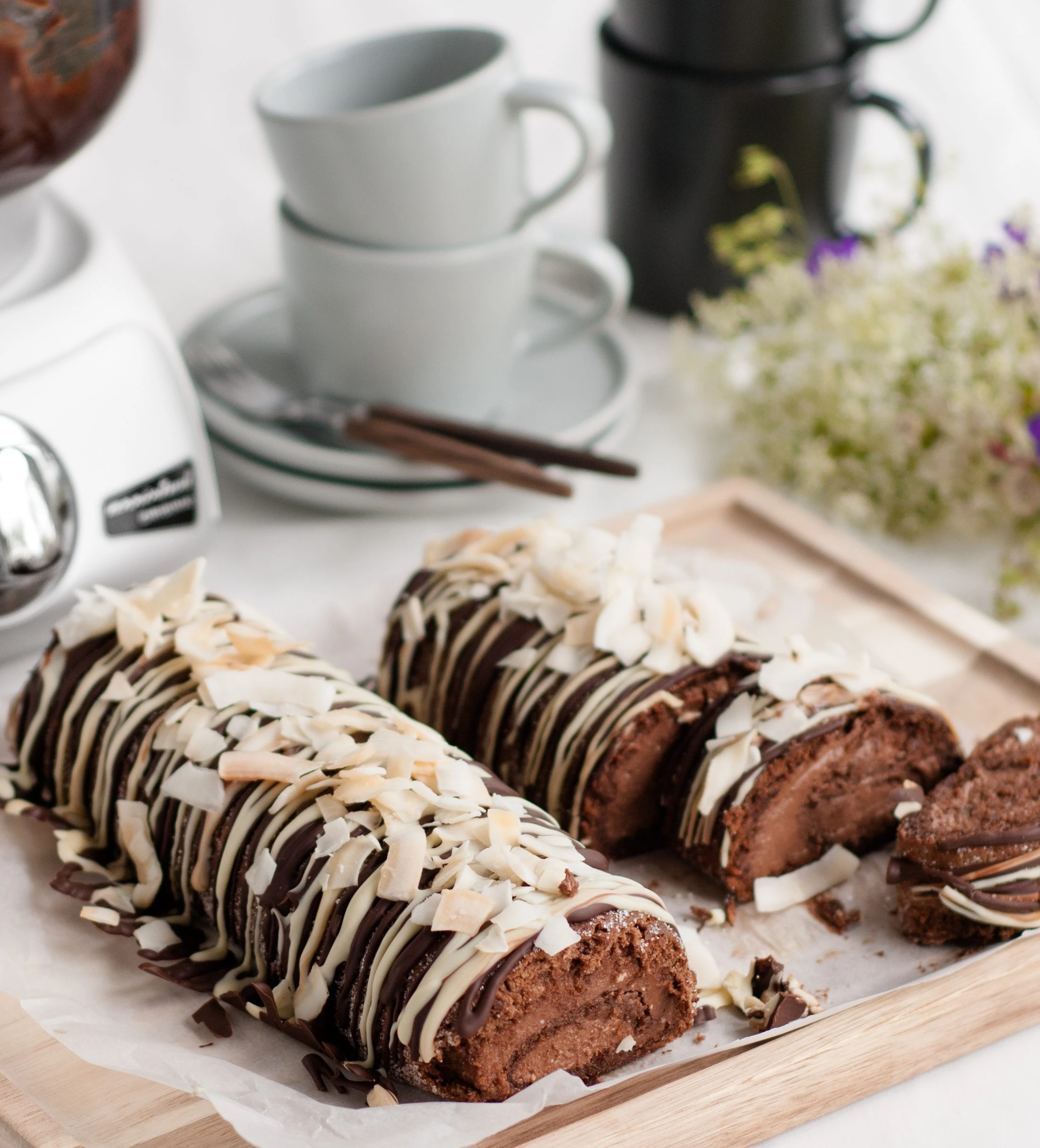 Chocolate Swiss roll cake topped with coconut flakes and chocolate drizzle, made with an Ankarsrum stand mixer.