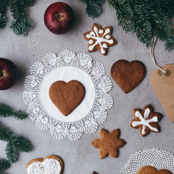 Heart-shaped Christmas gingerbread cookies surrounded with red apples