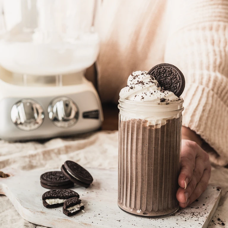 Oreo milkshake in a ribbed glass topped with whipped cream and an Oreo cookie, made with an Ankarsrum blender.