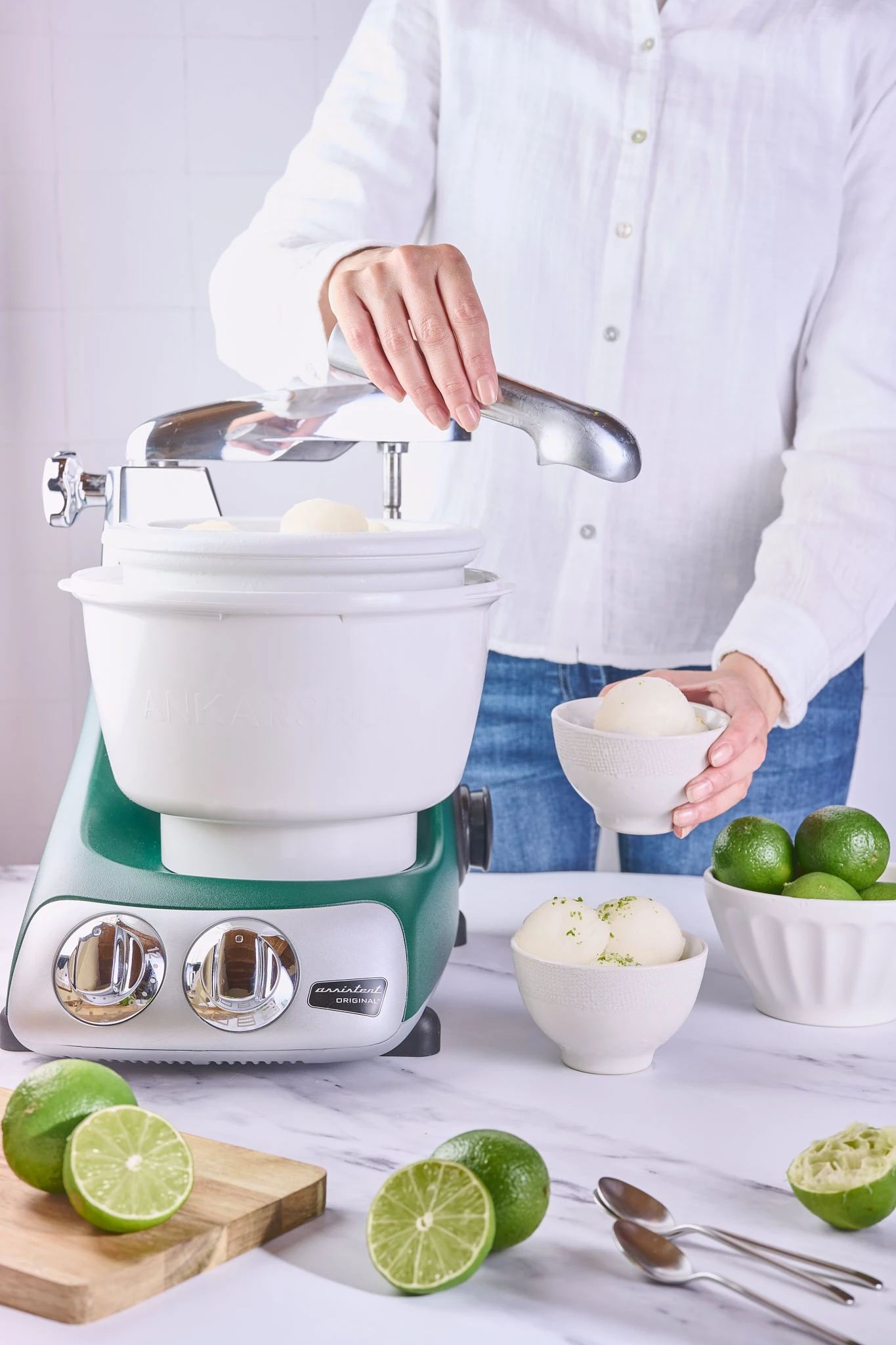 Woman making lime sorbet with a forest green Ankarsrum Original stand mixer and ice cream maker attachment.