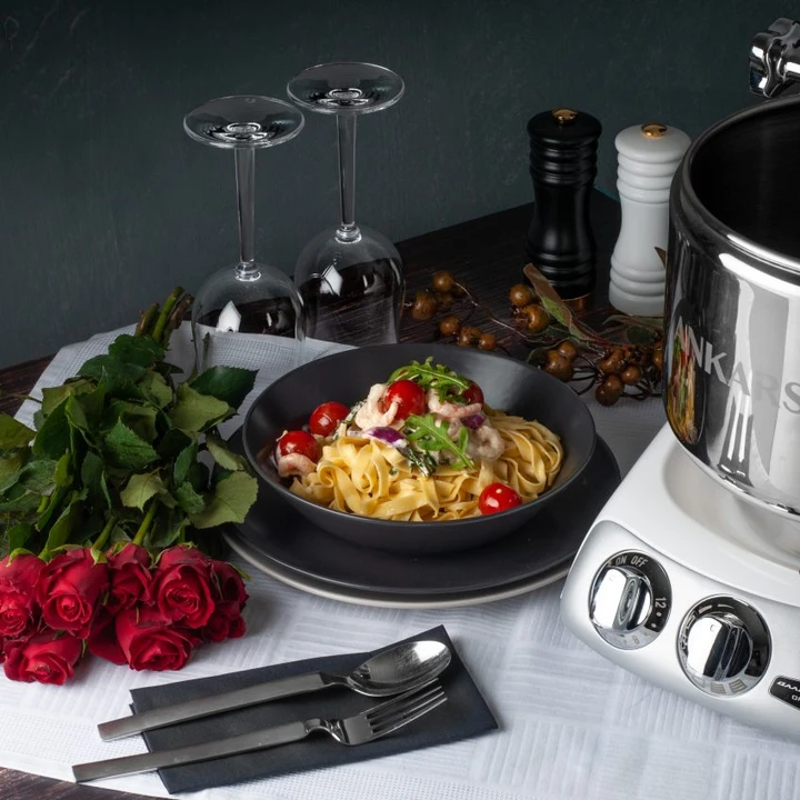 a picture of a table with roses, pasta, the kitchen machine, and cutlery.