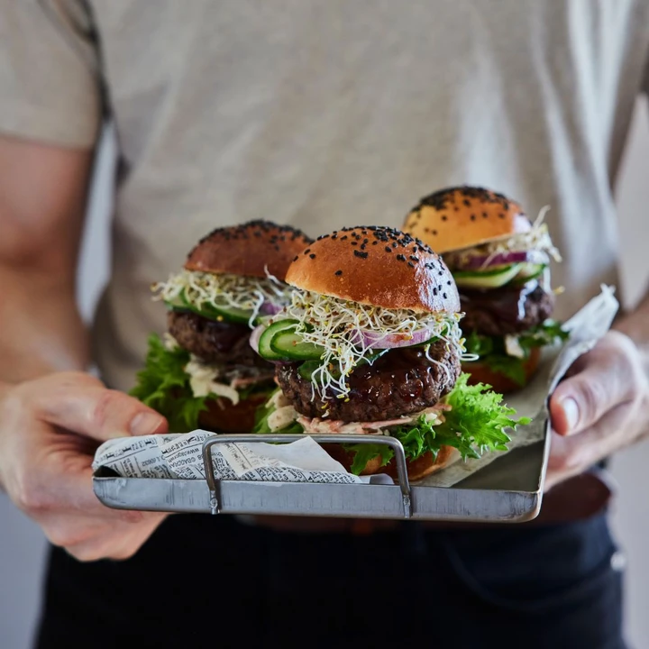 A person holding a delicious hamburger with fresh ingredients.