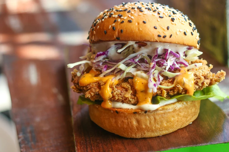 Crispy fried chicken burger with coleslaw and spicy sauce on a sesame seed bun, made with Ankarsrum stand mixer.