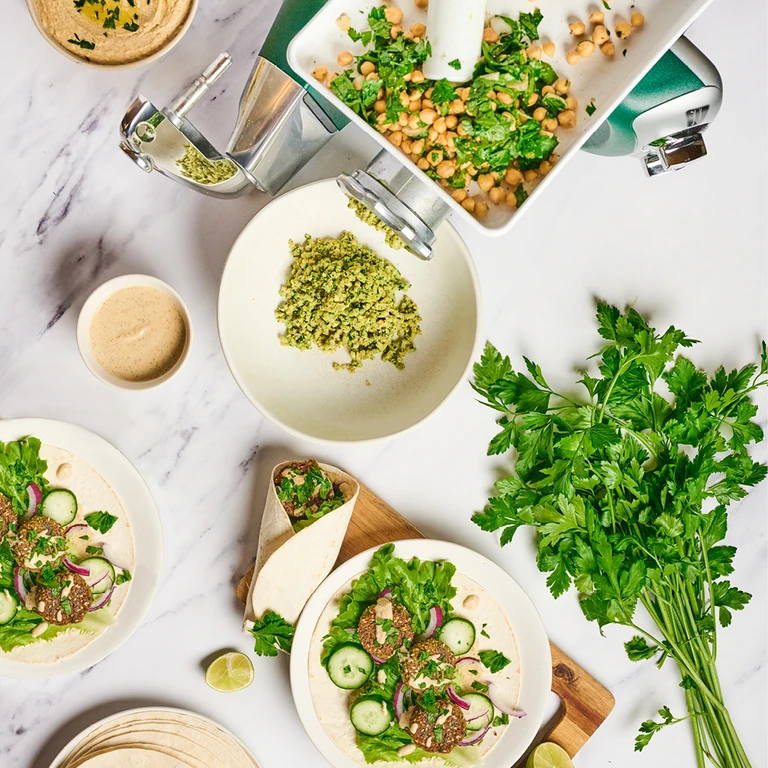 Ankarsrum stand mixer grinding chickpeas and herbs for falafel wraps with tahini, cucumber, red onion, and fresh parsley.