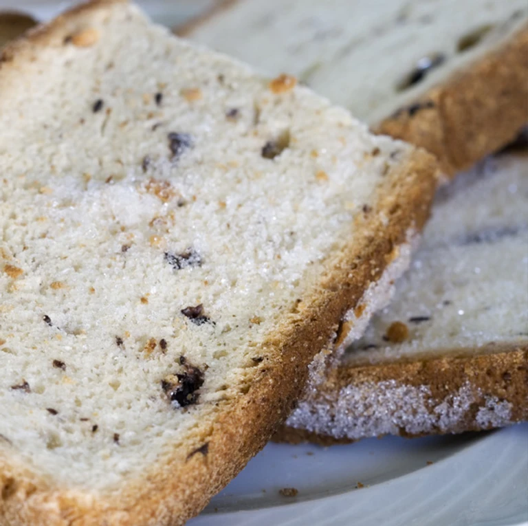 Freshly sliced homemade raisin bread with golden crust, made with Ankarsrum stand mixer, showing soft airy texture.