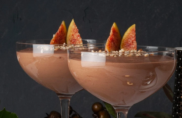 en bild på två glas med chokladmousse. en bukett rosor ligger brevid.