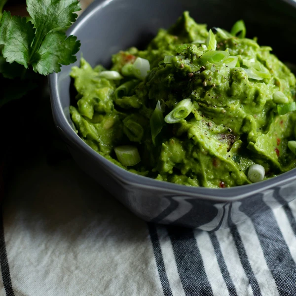 Creamy homemade guacamole prepared in a stand mixer, perfectly blended to a chunky or smooth consistency for the ultimate party dip.