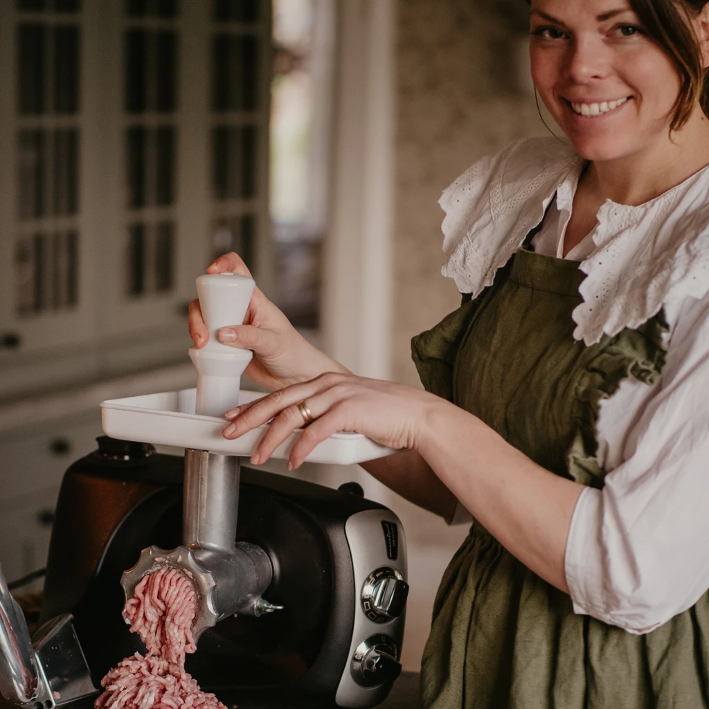 Julmys med hemlagat – kvinna maler kött med Ankarsrum köttkvarnstillbehör.