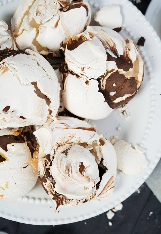 Chocolate-swirled meringue cookies with cracked shells on a white beaded plate, made with an Ankarsrum stand mixer.