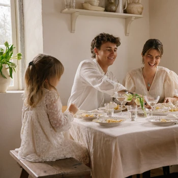Familj samlad runt ett ljust dukat bord och firar vårens högtider tillsammans i en varm och naturlig miljö.