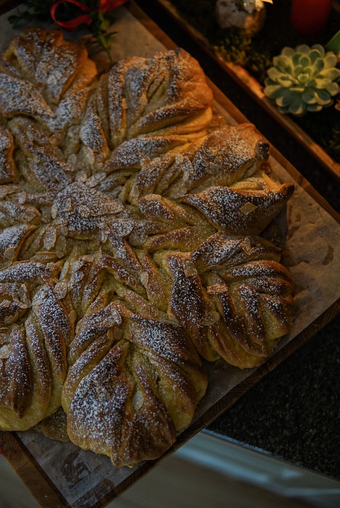 Festive star-shaped almond pastry dusted with powdered sugar, made with Ankarsrum stand mixer, on a wooden board.