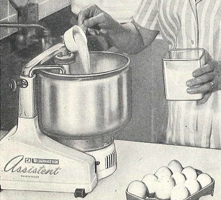Vintage Electrolux Assistent stand mixer ad showing a person adding ingredients, with eggs nearby.