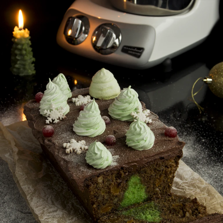 Christmas loaf cake with chocolate frosting, green meringue trees, snowflakes, and cranberries, made with Ankarsrum stand mixer.