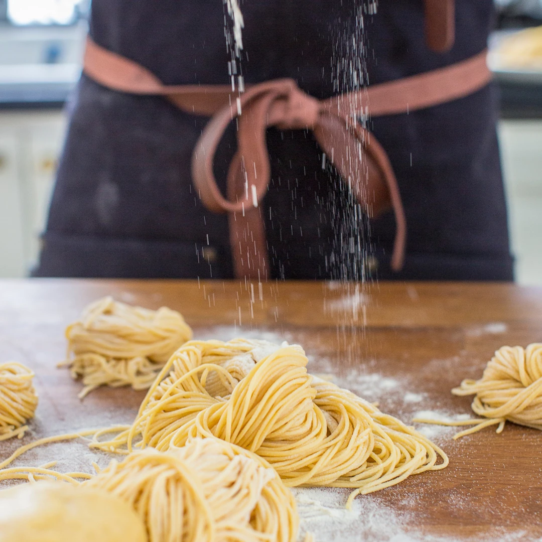 Färska pastanystan som pudras med mjöl medan någon förbereder dem med hjälp av Ankarsrums pastavalsar.